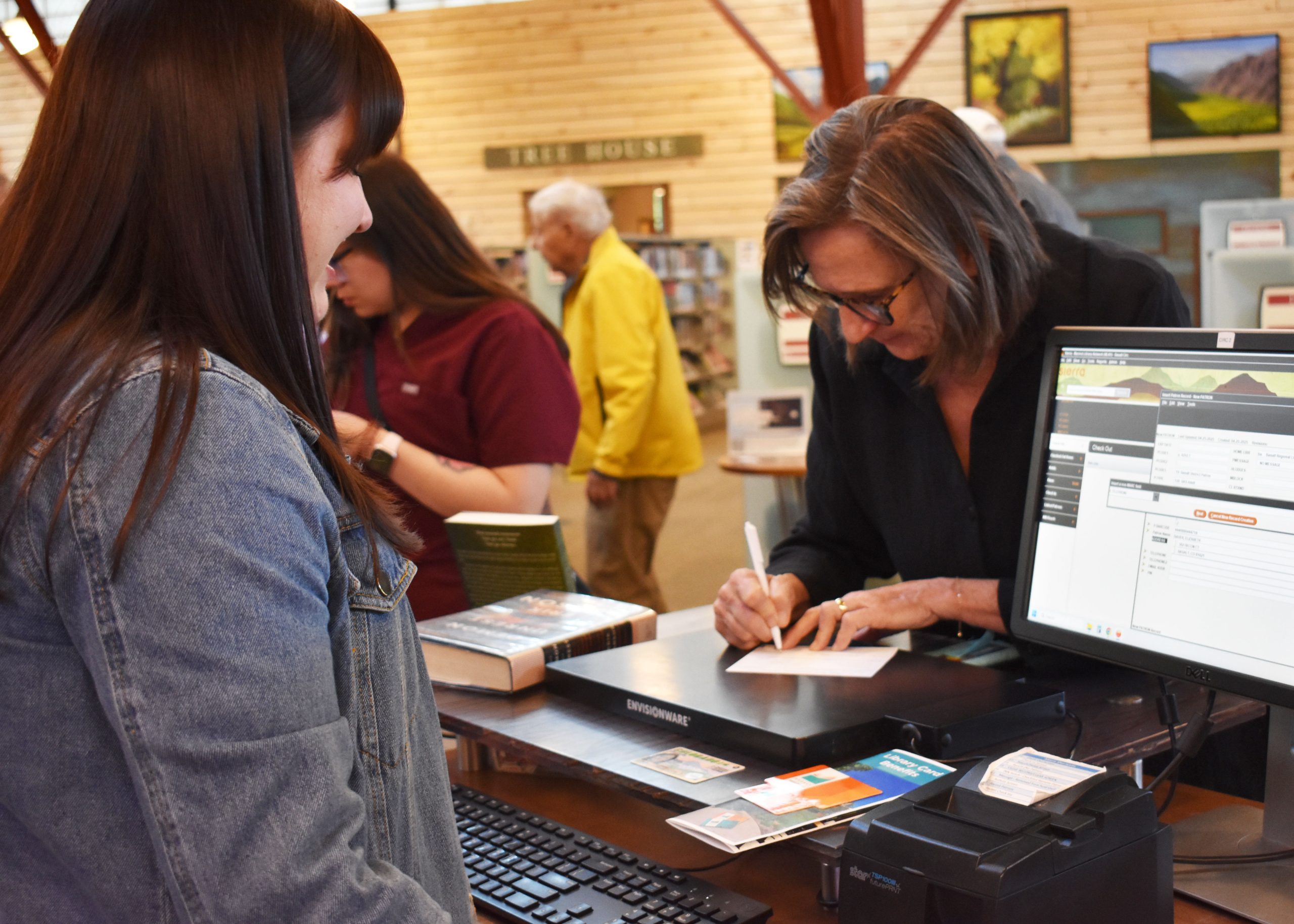 a staff member helping a person sign up for a library card