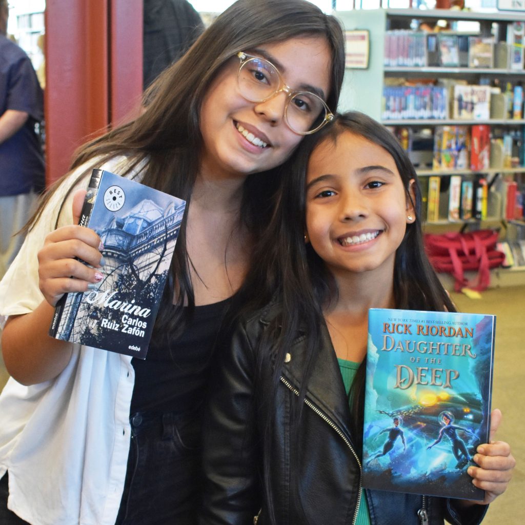 Two young girls holding up books during the annual library party in 2023